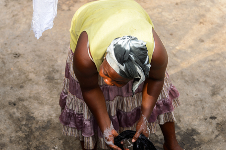 ACCRA, GHANA - JAN 8, 2017: Unidentified Ghanaian woman bends down to wash the clothes. People of Ghana suffer of poverty due to the economic situationのeditorial素材