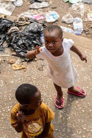 ACCRA, GHANA - JAN 8, 2017: Unidentified Ghanaian little kids play in the trash on the street. Children of Ghana suffer of poverty due to the economic situationのeditorial素材