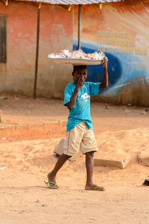 ACCRA, GHANA - JAN 8, 2017: Unidentified Ghanaian boy carries the basin on his head. Children of Ghana suffer of poverty due to the economic situationのeditorial素材