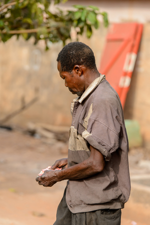ACCRA, GHANA - JAN 8, 2017: Unidentified Ghanaian old man counts money in his hands. People of Ghana suffer of poverty due to the economic situationのeditorial素材