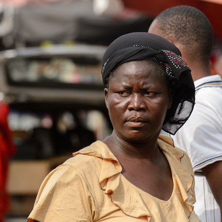 LOME, TOGO - Jan 9, 2017: Unidentified Togolese serious woman in a shirt and black headscarf at the Lome central market. Togo people suffer of poverty due to the bad economyのeditorial素材