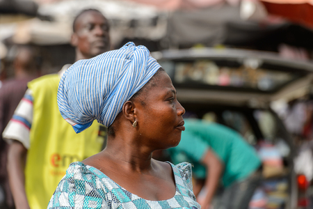 LOME, TOGO - Jan 9, 2017: Unidentified Togolese woman in blue and white headscarf looks away at the Lome central market. Togo people suffer of poverty due to the bad economyのeditorial素材