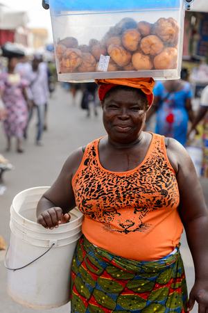 LOME, TOGO - Jan 9, 2017: Unidentified Togolese woman carries a basin on her head at the Lome central market. Togo people suffer of poverty due to the bad economyのeditorial素材