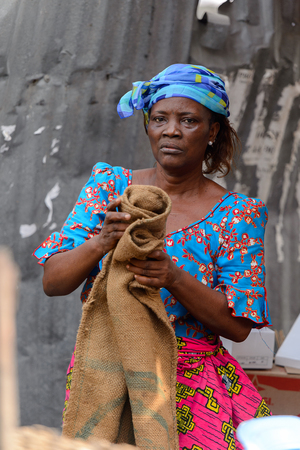 LOME, TOGO - Jan 9, 2017: Unidentified Togolese woman in blue headscarf and colored dress holds a...