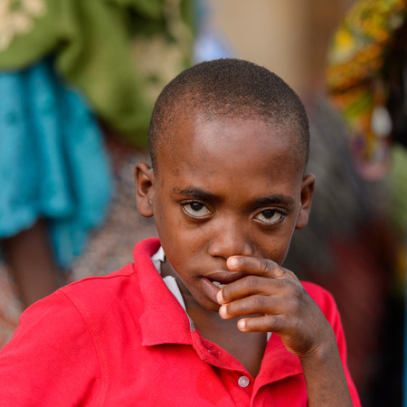 LOME, TOGO - Jan 9, 2017: Unidentified Togolese boy in red shirt  puts his finger into his mouth at the Lome central market. Togo people suffer of poverty due to the bad economyのeditorial素材