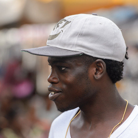 LOME, TOGO - Jan 9, 2017: Unidentified Togolese man in a white shirt and cap looks away at the Lome central market. Togo people suffer of poverty due to the bad economyのeditorial素材