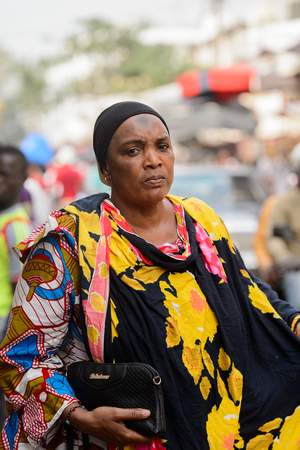 LOME, TOGO - Jan 9, 2017: Unidentified Togolese woman in colored dress and black headcrarf at the Lome central market. Togo people suffer of poverty due to the bad economyのeditorial素材