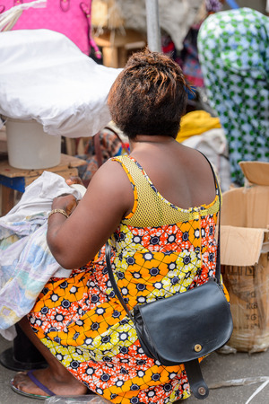 LOME, TOGO - Jan 9, 2017: Unidentified Togolese woman in colored dress from behind at the Lome central market. Togo people suffer of poverty due to the bad economyのeditorial素材