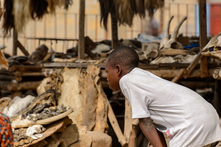 LOME, TOGO - Jan 9, 2017: Unidentified Togolese boy in white shirt bends down at the Lome fetish market. Togo people suffer of poverty due to the bad economyのeditorial素材