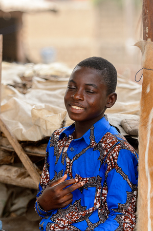 LOME, TOGO - Jan 9, 2017: Unidentified Togolese boy in blue shirt closes his eyes at the Lome fetish market. Togo people suffer of poverty due to the bad economyのeditorial素材