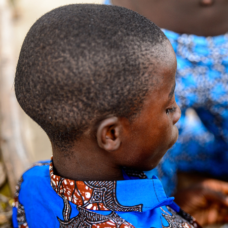 LOME, TOGO - Jan 9, 2017: Unidentified Togolese boy in blue shirt looks down at the Lome fetish market. Togo people suffer of poverty due to the bad economyのeditorial素材