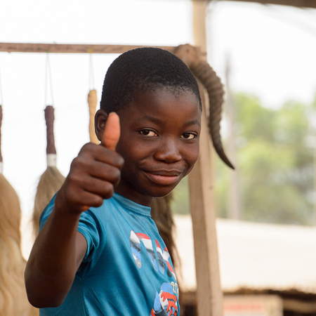 LOME, TOGO - Jan 9, 2017: Unidentified Togolese boy in blue shirt shows his thumb at the Lome fetish market. Togo people suffer of poverty due to the bad economyのeditorial素材