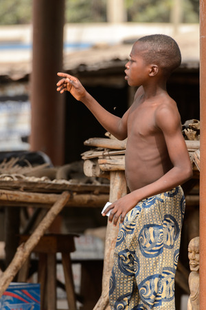 LOME, TOGO - Jan 9, 2017: Unidentified Togolese boy in pants looks away at the Lome fetish market. Togo people suffer of poverty due to the bad economyのeditorial素材