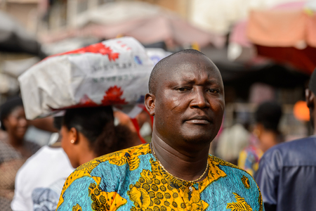 LOME, TOGO - Jan 9, 2017: Unidentified Togolese man in colored shirt looks away at the Lome central market. Togo people suffer of poverty due to the bad economyのeditorial素材