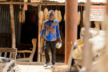 LOME, TOGO - Jan 9, 2017: Unidentified Togolese boy in blue shirt holds a bowl in his hand at the Lome fetish market. Togo people suffer of poverty due to the bad economyのeditorial素材