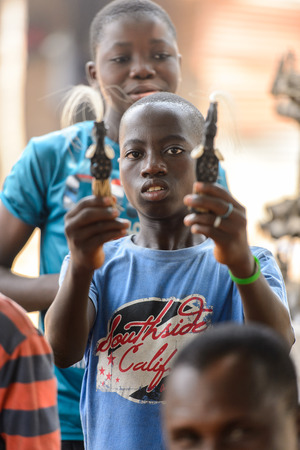 LOME, TOGO - Jan 9, 2017: Unidentified Togolese young boy holds a couple of figures to sell at the Lome fetish market. Togo people suffer of poverty due to the bad economyのeditorial素材