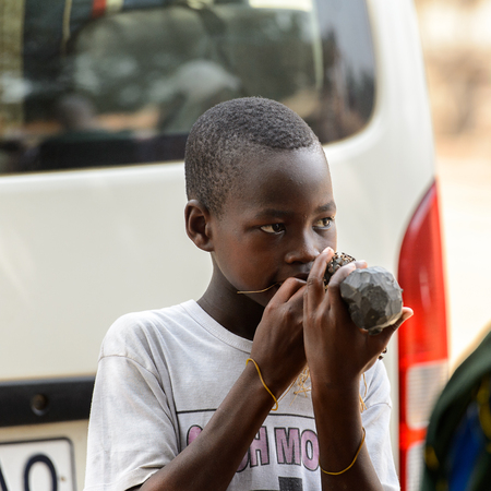 LOME, TOGO - Jan 9, 2017: Unidentified Togolese boy puts an unknown object in his mouth at the Lome fetish market. Togo people suffer of poverty due to the bad economyのeditorial素材