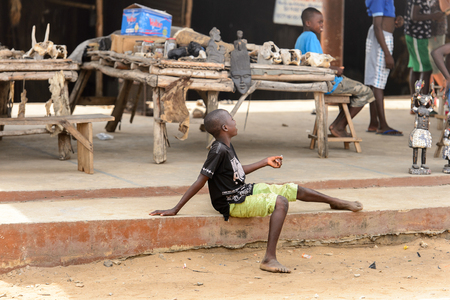LOME, TOGO - Jan 9, 2017: Unidentified Togolese boy sits on the verge of the road at the Lome fetish market. Togo people suffer of poverty due to the bad economyのeditorial素材