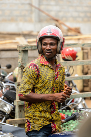 LOME, TOGO - Jan 9, 2017: Unidentified Togolese man in helmet stands at the Lome port. Togo people suffer of poverty due to the bad economyのeditorial素材