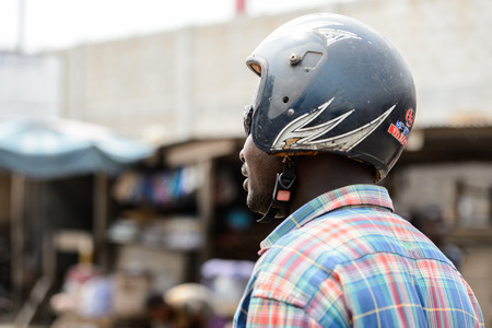 LOME, TOGO - Jan 9, 2017: Unidentified Togolese man in helmet from behind at the Lome port. Togo people suffer of poverty due to the bad economyのeditorial素材