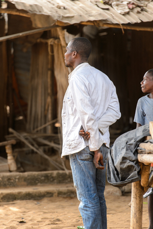 LOME, TOGO - Jan 9, 2017: Unidentified Togolese man in white shirt crosses his hands behind his back at the Lome fetish market. Togo people suffer of poverty due to the bad economyのeditorial素材