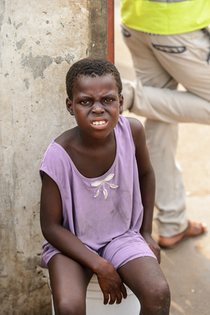 LOME, TOGO - Jan 9, 2017: Unidentified Togolese young girl in purple shirt shows her teeth at the Lome port. Togo children suffer of poverty due to the bad economyのeditorial素材
