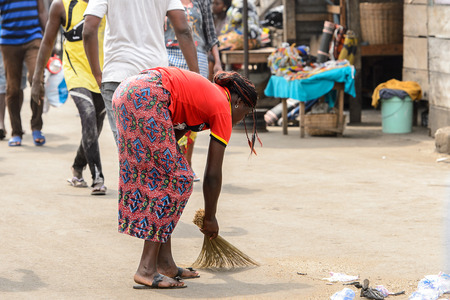 LOME, TOGO - Jan 9, 2017: Unidentified Togolese woman sweeps the ground at the Lome port. Togo people suffer of poverty due to the bad economyのeditorial素材