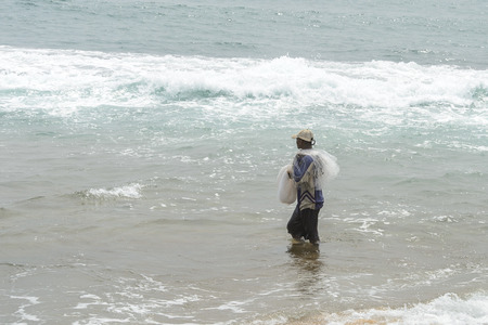LOME, TOGO - Jan 9, 2017: Unidentified Togolese man holds a fishnet on the coast of the Gulf of Guinea. Togo people suffer of poverty due to the bad economyのeditorial素材