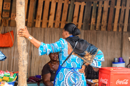 LOME, TOGO - Jan 9, 2017: Unidentified Togolese woman in blue dress from behind at the Lome port. Togo people suffer of poverty due to the bad economyのeditorial素材