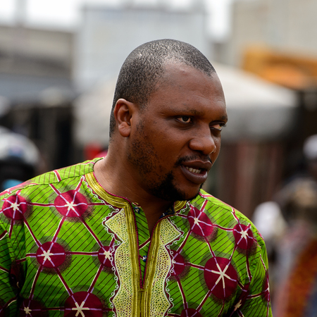 LOME, TOGO - Jan 9, 2017: Unidentified Togolese man in green shirt looks away at the Lome port. Togo people suffer of poverty due to the bad economyのeditorial素材
