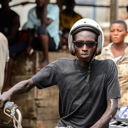 LOME, TOGO - Jan 9, 2017: Unidentified Togolese man in helmet rides the motocycle at the Lome port. Togo people suffer of poverty due to the bad economyのeditorial素材
