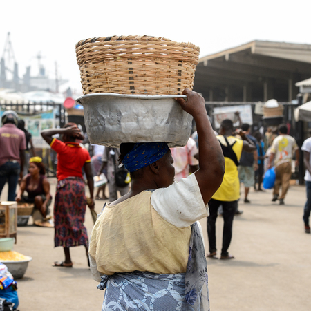 LOME, TOGO - Jan 9, 2017: Unidentified Togolese woman carries a basin on her head at the Lome port. Togo people suffer of poverty due to the bad economyのeditorial素材