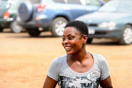LOME, TOGO - Jan 9, 2017: Unidentified Togolese woman in grey shirt smiles at the Lome port. Togo people suffer of poverty due to the bad economyのeditorial素材