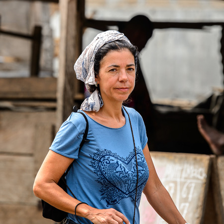 LOME, TOGO - Jan 9, 2017: Unidentified European woman in white headscarf at the Lome port. Togo people suffer of poverty due to the bad economyのeditorial素材