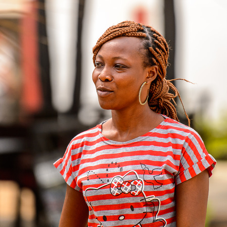 LOME, TOGO - Jan 9, 2017: Unidentified Togolese woman in colored shirt with braids and big earing. Togo people suffer of poverty due to the bad economyのeditorial素材