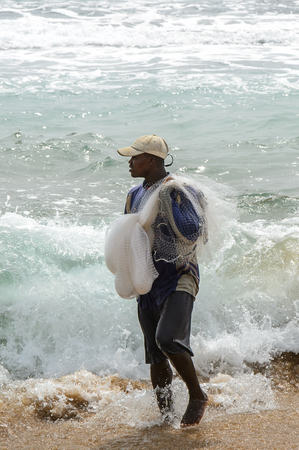 LOME, TOGO - Jan 9, 2017: Unidentified Togolese man holds a fishnet on the coast of the Gulf of Guinea. Togo people suffer of poverty due to the bad economyのeditorial素材