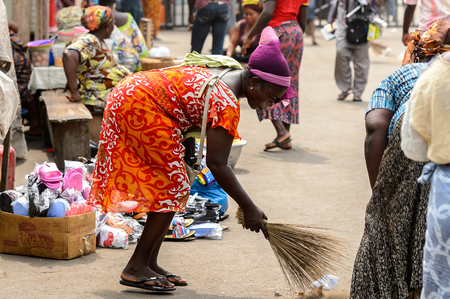 LOME, TOGO - Jan 9, 2017: Unidentified Togolese woman sweeps the ground at the Lome port. Togo people suffer of poverty due to the bad economyのeditorial素材