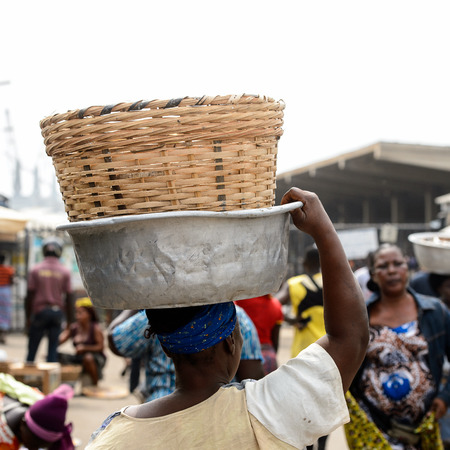 LOME, TOGO - Jan 9, 2017: Unidentified Togolese woman carries a basin on her head at the Lome port. Togo people suffer of poverty due to the bad economyのeditorial素材