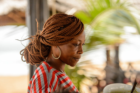 LOME, TOGO - Jan 9, 2017: Unidentified Togolese woman in colored shirt with braids and big earing. Togo people suffer of poverty due to the bad economyのeditorial素材