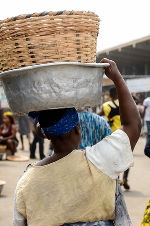 LOME, TOGO - Jan 9, 2017: Unidentified Togolese woman carries a basin on her head at the Lome port. Togo people suffer of poverty due to the bad economyのeditorial素材