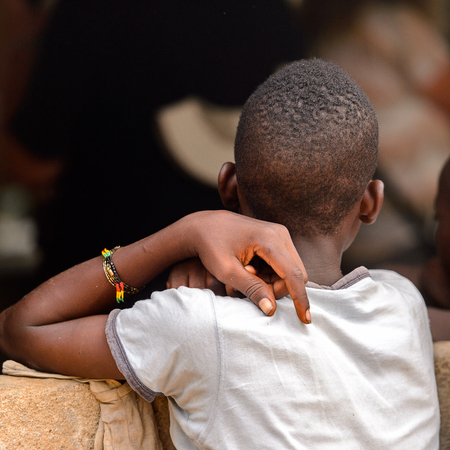 LOME, TOGO - Jan 9, 2017: Unidentified Togolese young boy from behind near the local shaman's house. Togo people suffer of poverty due to the bad economyのeditorial素材
