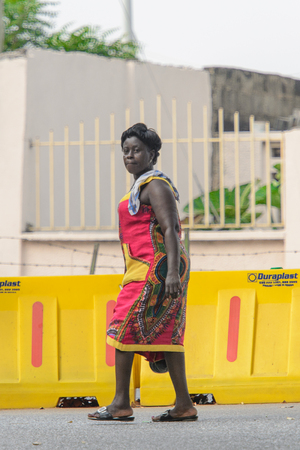 ACCRA, GHANA - Jan 8, 2017: Unidentified Ghanaian woman walks across yellow fencing . People of Ghana suffer of poverty due to the economic situationのeditorial素材