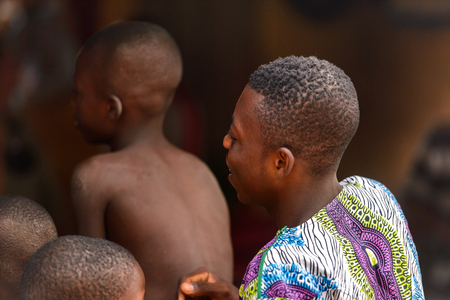 LOME, TOGO - Jan 9, 2017: Unidentified Togolese young boys from behind near the local shaman's house. Togo people suffer of poverty due to the bad economyのeditorial素材