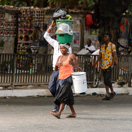 ACCRA, GHANA - Jan 8, 2017: Unidentified Ghanaian woman carries a basket on her head. People of Ghana suffer of poverty due to the economic situationのeditorial素材
