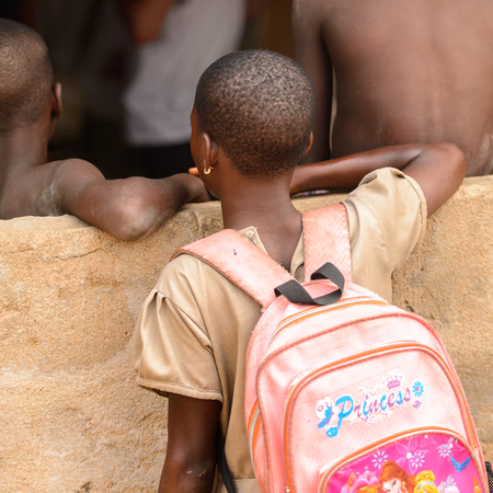 LOME, TOGO - Jan 9, 2017: Unidentified Togolese young girl carries a backpack near the local shaman's house. Togo people suffer of poverty due to the bad economyのeditorial素材