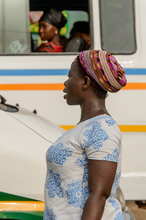 ACCRA, GHANA - Jan 8, 2017: Unidentified Ghanaian woman in white and blue shirt and a hat looks away. People of Ghana suffer of poverty due to the economic situationのeditorial素材