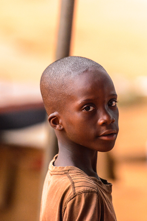 OUIDAH, BENIN - Jan 9, 2017: Unidentified Beninese boy in brown shirt looks around. Benin children suffer of poverty due to the bad economyのeditorial素材