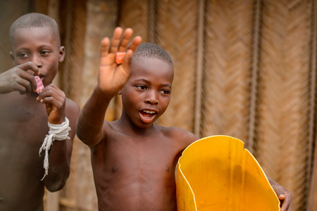 LOME, TOGO - Jan 9, 2017: Unidentified Togolese young boy with yellow bucket in his hand waves. Togo children suffer of poverty due to the bad economyのeditorial素材
