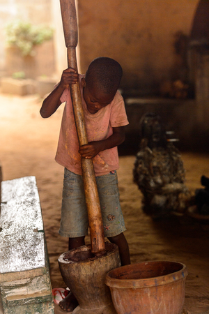 LOME, TOGO - Jan 9, 2017: Unidentified Togolese young boy holds a wooden stick in the local shaman's house. Togo children suffer of poverty due to the bad economyのeditorial素材