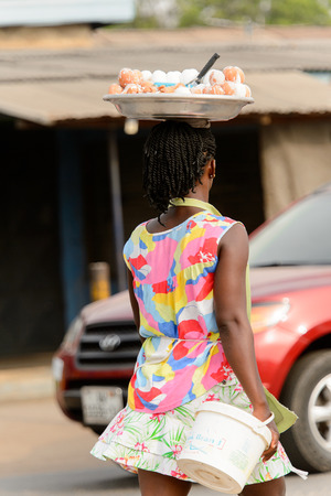 ACCRA, GHANA - Jan 8, 2017: Unidentified Ghanaian woman carries a basin on her head. People of Ghana suffer of poverty due to the economic situationのeditorial素材